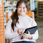 Adolescent with Down syndrome holding computer tablet.