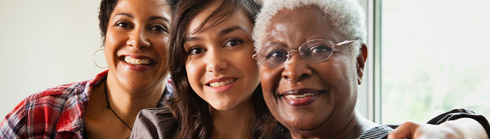 Three generations of women smiling for a family photo.