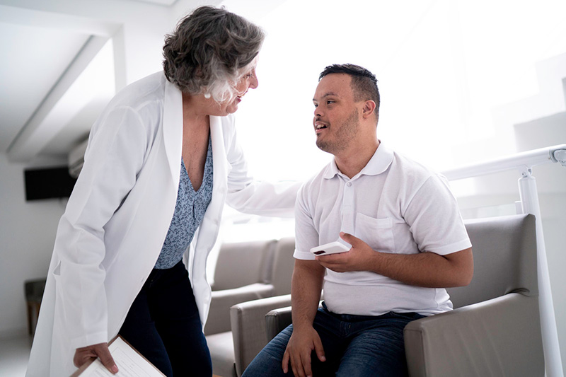 An older person with Down syndrome speaking with a health care provider.