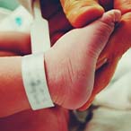 Closeup of adult hand holding infant foot.