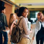 Teenagers with backpacks in a school hallway.